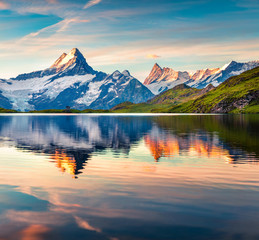 Colorful summer sunrise on Bachalpsee lake with Schreckhorn peak on background.