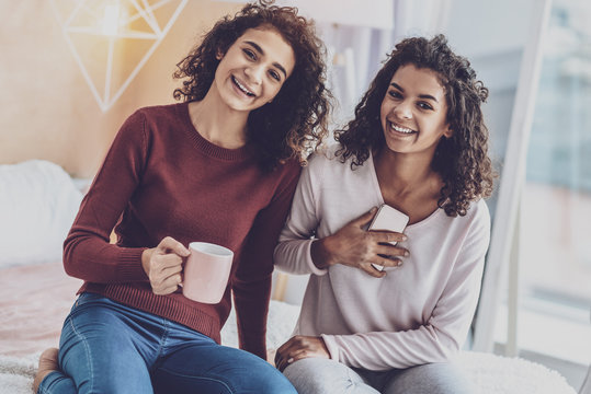 Warming up. Amazing curly haired brunette smiling cheerfully while being at home
