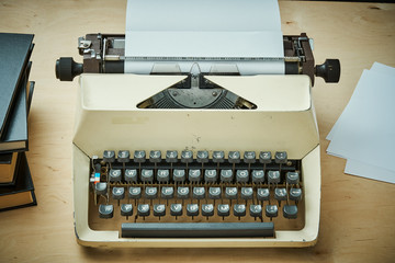 bright old typewriter with gray keys and books on a wooden table