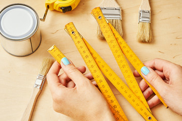 woman holding a ruler in her hands over a wooden table with tools