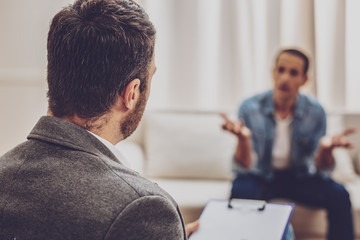 Be attentive. Upset brunette man actively gesticulating while discussing his problems with...