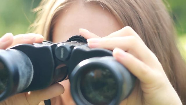 Woman tourist looking through binoculars closeup. Watch the object, spy.