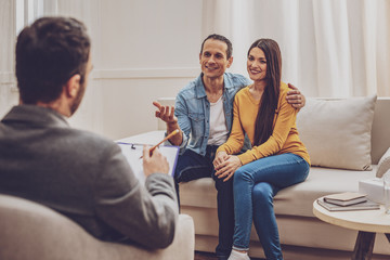 Happy together. Attractive longhaired woman keeping smile on her face while sitting near her