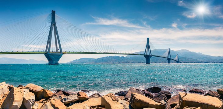 Sunny morning panorama of Rion-Antirion Bridge. Colorful spring view of the Gulf of Corinth, Greece, Europe. Beauty of countryside concept background. Artistic style post processed photo.
