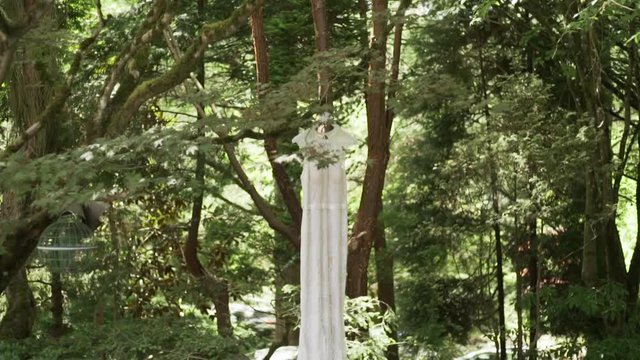 Vintage wedding dress hanging in the forest.