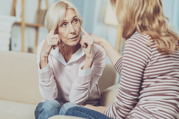 Sad mood. Nice senior woman touching her temples while feeling unhappy