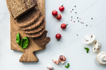flat lay with cut bread on wooden cutting board, black pepper and vegetables for cooking breakfast...