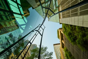 Low Angle Shot von modernen Glasgebäuden und grün mit klarem Himmelshintergrund. © jamesteohart