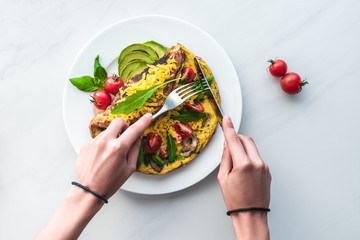 partial view of woman cutting homemade omelette for breakfast at white marble surface