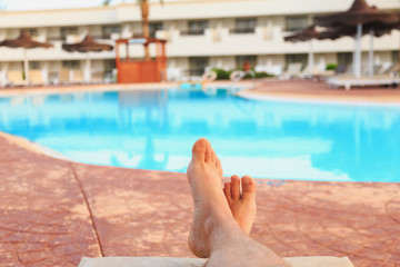 male feet on swimming pool background