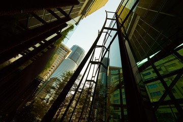 Low angle shot of modern glass buildings and green with clear sky background.