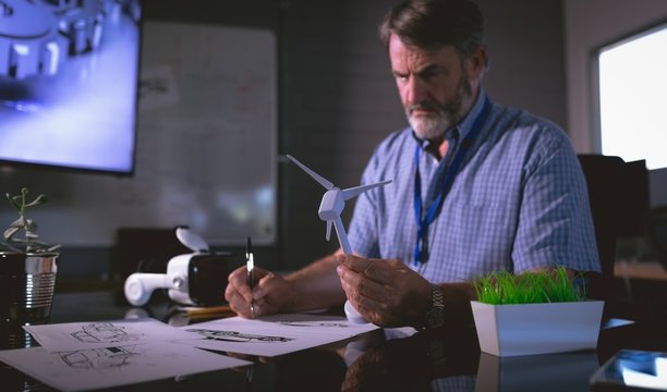 Male Executive Examining A Windmill Model