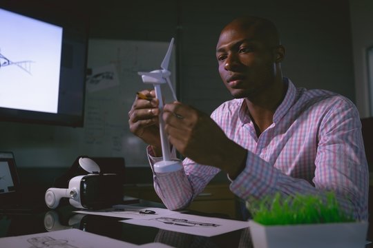 Male executive examining a windmill model