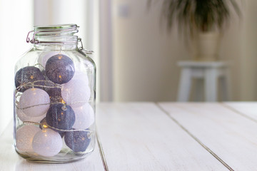 Big glass jar filled with lightning lampions standing on a wooden table