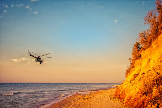 Military helicopter flying above the sea coast on an early morning