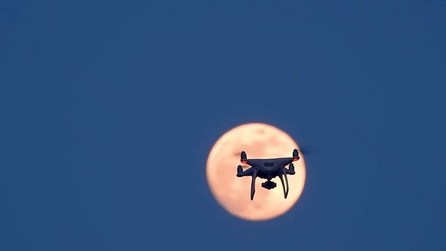 Drone flying in front of fullmoon in sunset