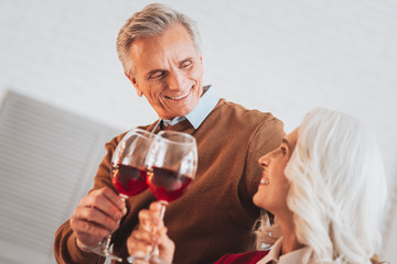 Pleasant atmosphere. Cheerful mature man keeping smile on his face while looking at his wife