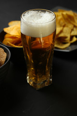 Light beer in a glass bowl on a black background.Beer in the bar and snacks, chips, nuts.