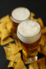 Light beer in a glass bowl on a black background.Beer in the bar and snacks, chips, nuts.