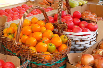 Organic, fresh tomatoes in wicker basket are sold at local vegetable farming market. Sale of...