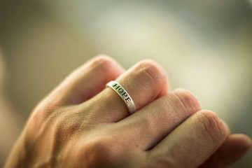 A young woman's hand wearing a ring on her marriage finger saying 