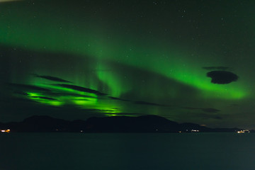 norwegian aurora borealis with mountains and water, view from hurtigruten ship boat, norway, europe, green northern lights