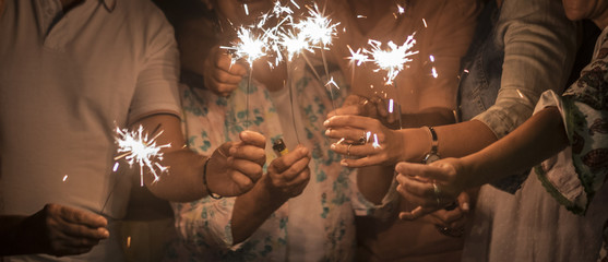 panoramic view of group of friends mixed ages celebrate together in the night with sparkles file...