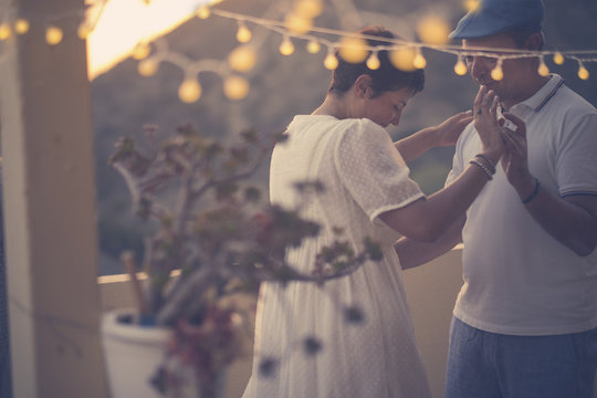 romantic couple dance together with love and romance during the down in the evening at home in the terrace. outdoor leisure activity for middle age woman and man. yellow light and nature in background