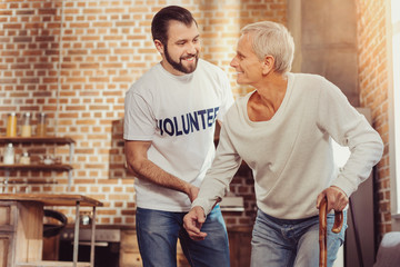 Always here. Satisfied paralyzed aged man trying to stand with help of a cane looking at a...