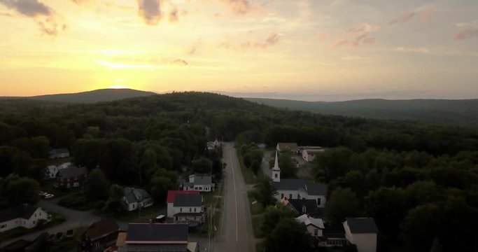Beautiful sunset behind mountains as drone glides over northen town of Monson, Maine.