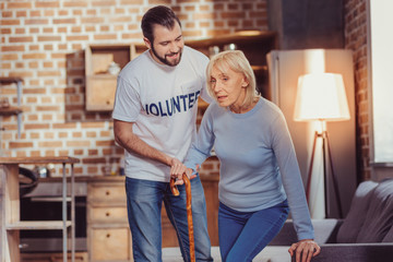 I will do this. Concentrated ill senior woman being in the bright room with a volunteer holding a...