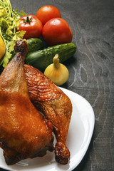 Chicken legs roasted on a barbeque and fresh organic vegetables on a black background. Copy space. Dietary food