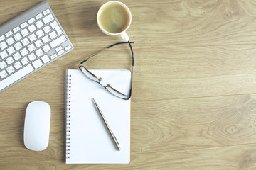 office desk table with computer keyboard, notebook with pen and coffee cup on desk