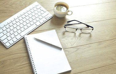 office desk table with computer keyboard, notebook with pen and coffee cup on desk