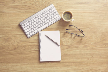 office desk table with computer keyboard, notebook with pen and coffee cup on desk