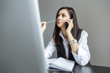 Thoughtful young woman talking on the phone in the office.