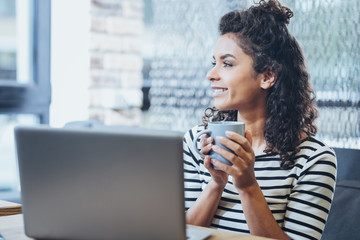 Love my work. Glad female freelancer drinking coffee while looking through window