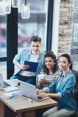Huge revenue. Jovial three colleagues working at cafe while staring at camera
