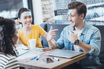Guess who. Optimistic three friends playing game while man pointing at himself