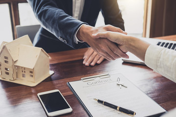 Real estate agent and customers shaking hands together celebrating finished contract after about...