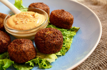 Freshly cooked falafel on a wooden table with tahini sauce.Eastern vegetarian meal of chickpea.Selective focus.