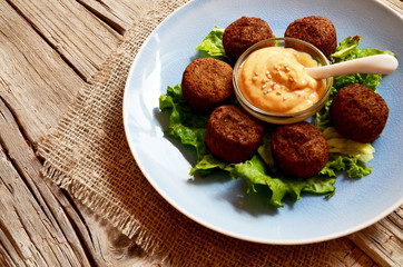 Freshly cooked falafel on a wooden table with tahini sauce.Eastern vegetarian meal of chickpea.Selective focus.