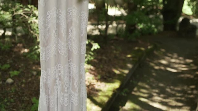 Vintage wedding dress hanging in the forest.