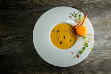 top view of fresh pumpkin cream soup with orange macaroon decoration