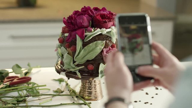People Taking Pictures of a Flower Cake with Cell Phones