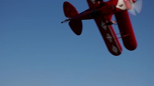 Aerobatic Pitts S2B biplane performs a turn away from the camera during a low pass.