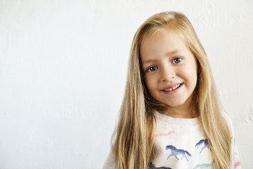 Portrait of happy little girl with long blonde hair smilng and showing positive emotions. Funny...