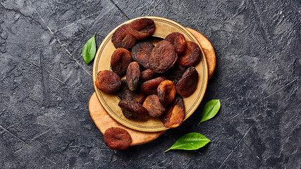 Brown sun dried apricots on black table. Top view of dry fruits with copy space.