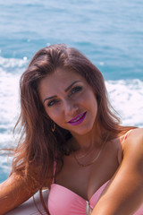 Portrait young beautiful brunette girl sitting on the luxury yacht in a bathing suit. Girls sunbathing. Girl with long hair enjoying a cruise on a yacht.