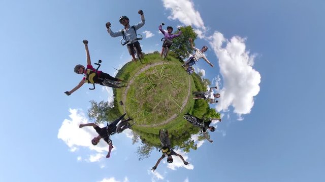 Spinning 4k 360 vr of bikers around a tiny planet holding up their arms in success.